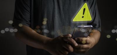 Person holding a phone and a yellow yield sign